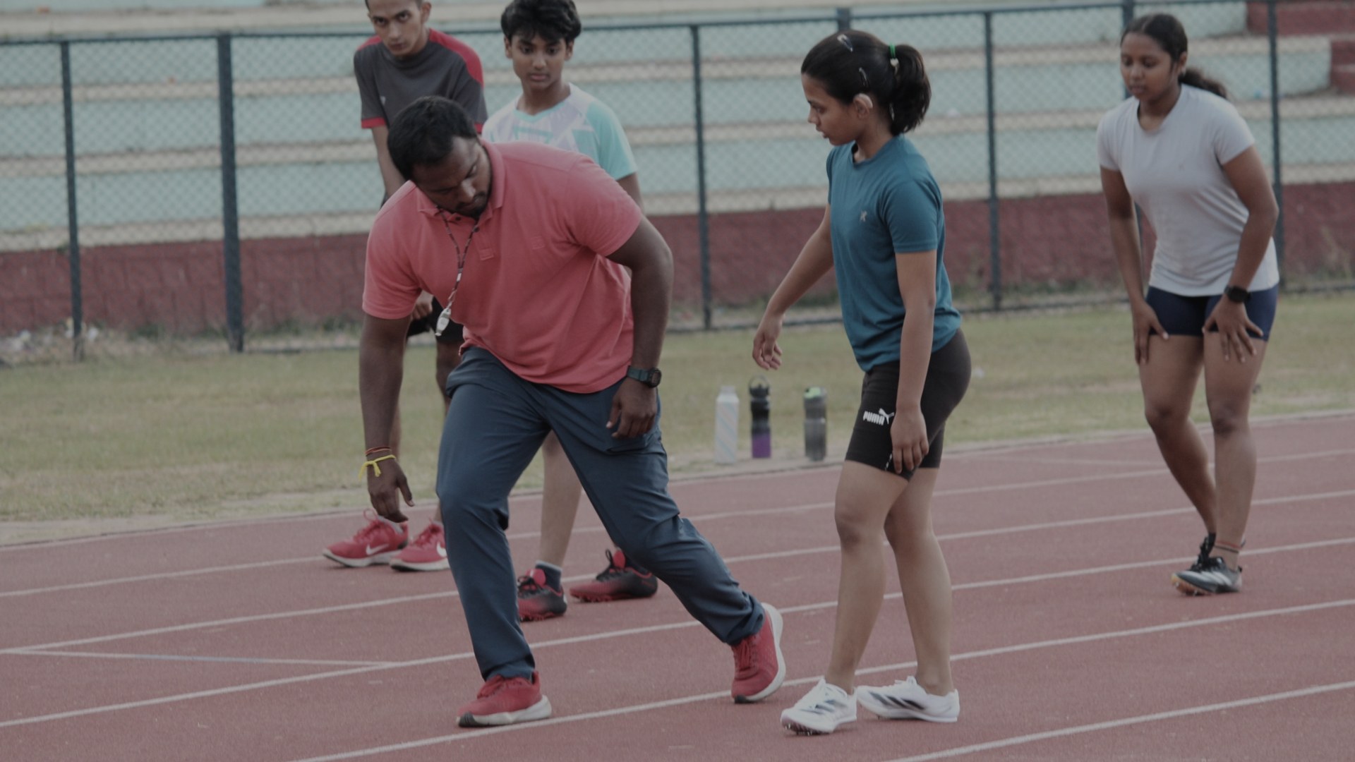 Radesh guiding young athletes through a running drill on the track