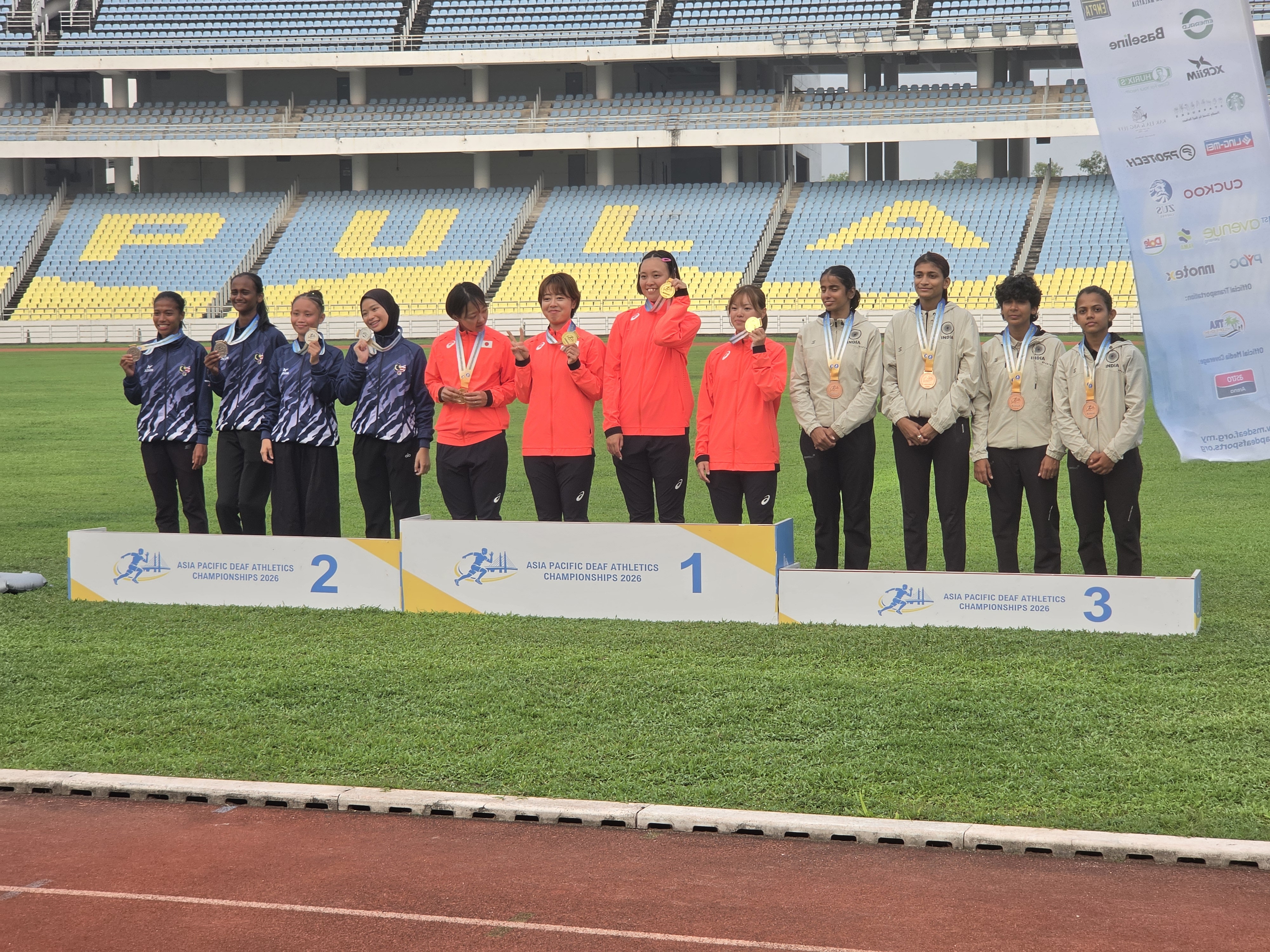 Relay medallists on the international podium, with the Indian team wearing bronze medals